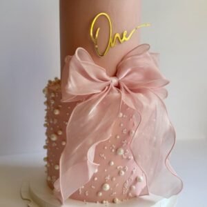 Two tier pink cake with pink bow and pearls