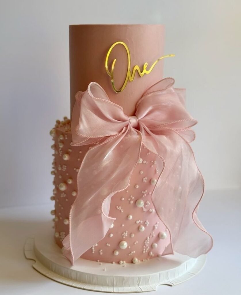 Two tier pink cake with pink bow and pearls