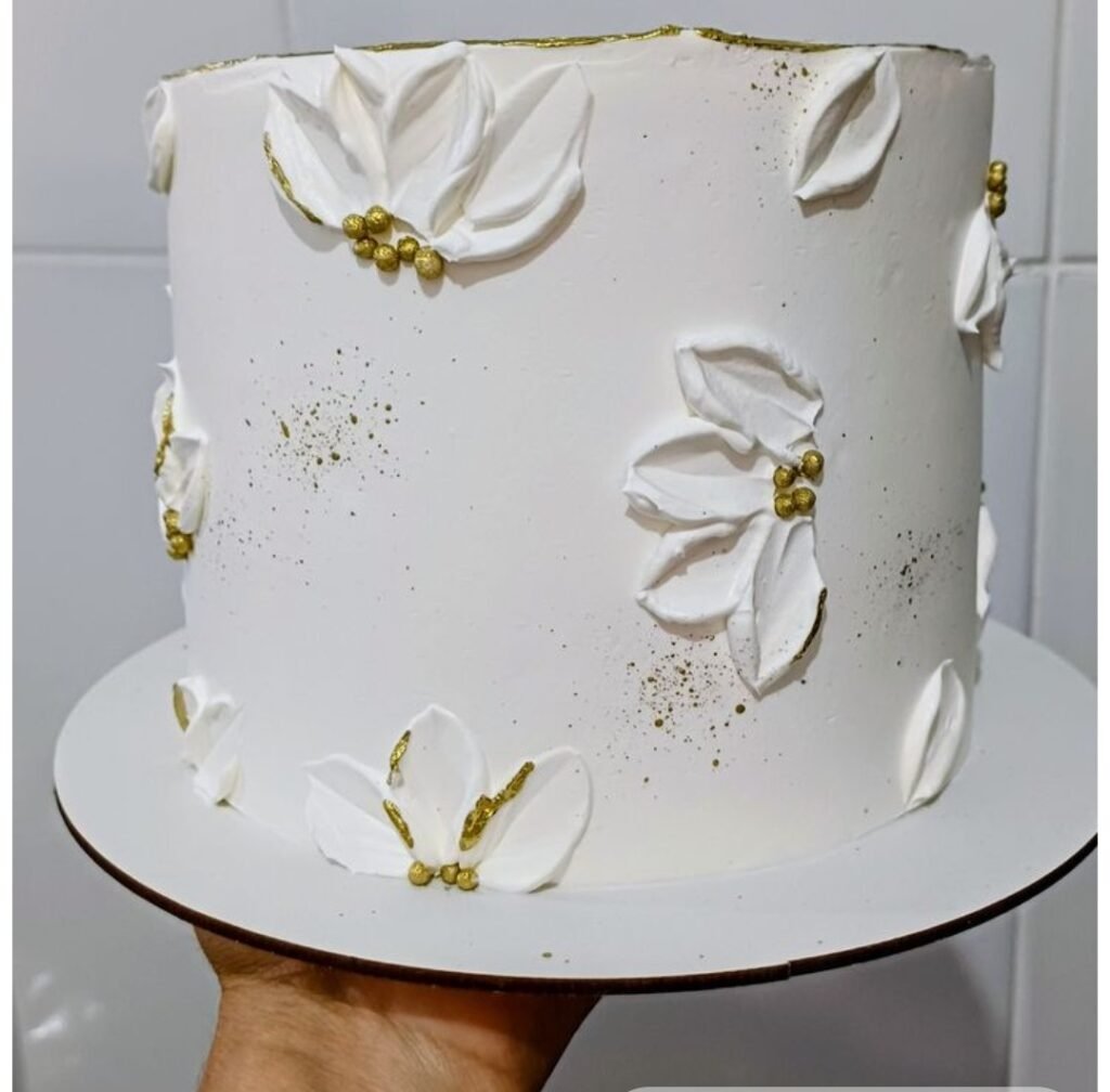 White cream cake with petals and golden beads