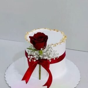 White cake with red rose tied with red ribbon