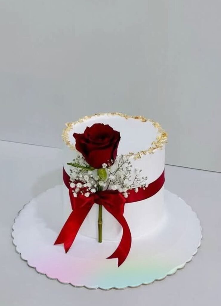 White cake with red rose tied with red ribbon